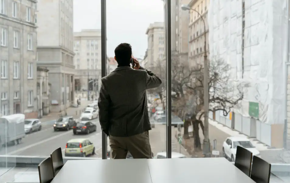 Mann mit Handy am Fenster