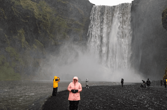 Visitors admire the majestic Skogafoss waterfall in Iceland's stunning landscape.
